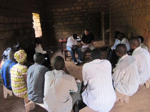 Photo of Rwandan farmers huddled in rudimentary classroom with clickers in hand