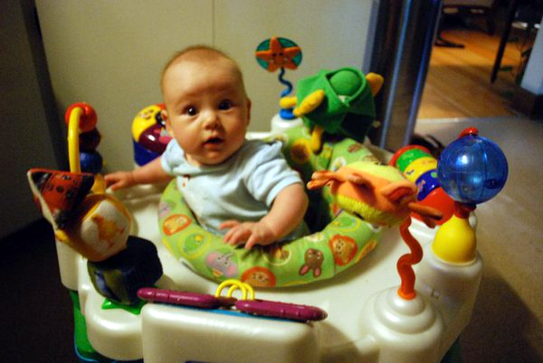 A baby in a mobile chair surrounded by toys