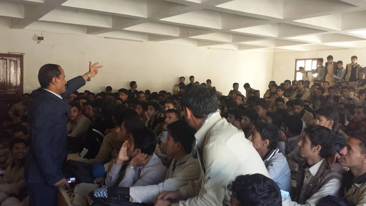 A crowded classroom with young men sitting in every available space