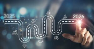 A wavy path weaves among icons representing business goals, going from 2025 toward 2026. A pointing finger touches the endpoint. The icons and path are white on a blue background with a blurred cityscape.