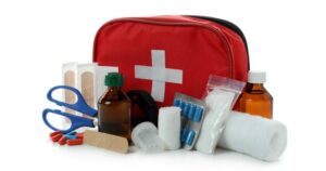 A red first aid pouch with its contents, including Band-Aids, gauze bandages, scissors, and more