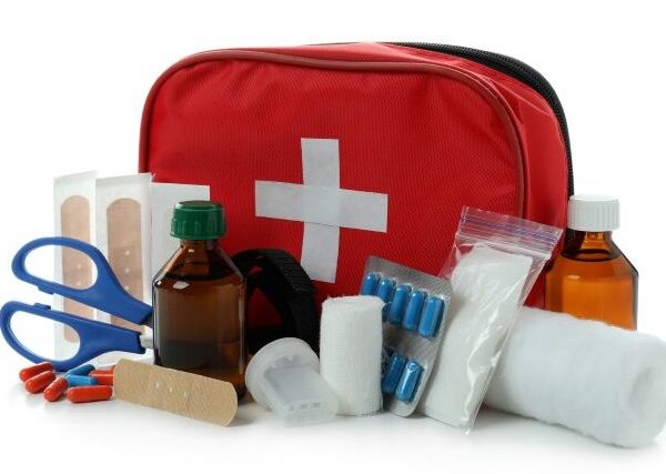 A red first aid pouch with its contents, including Band-Aids, gauze bandages, scissors, and more