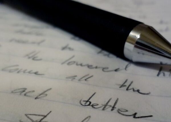 A black pen rests on a piece of paper with words in black ink