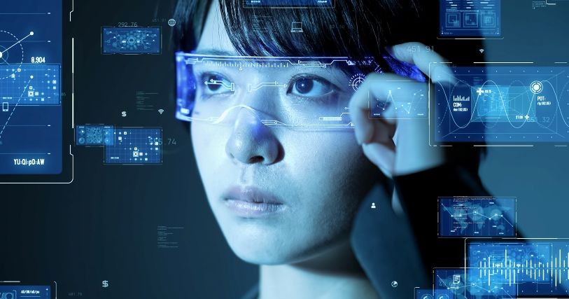 A dark-haired Asian woman wears smart glasses, Charts and data in rectangles overlay the image, simulating information she can see using the wearables