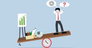 A man stands on a see-saw, balanced on a clock, that is tipping toward the other end, where a box of files, a laptop, and a bar chart weigh it down. Word clouds with a question mark and a tangled ball of string above the man's head signify confusion and pressure.