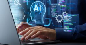 Hands hover over a laptop keyboard; above the hands are graphic images of a human head with AI superimposed, gears, and boxes with colored text boxes